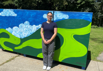 Kelsie Mulgrew standing with the recycling bins she painted at the John C. Hart Memorial Library in Yorktown. Photo courtesy of 