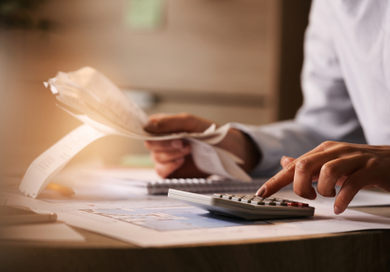 closeup economist using calculator while going through bills taxes office. Image by Drazen Zigic on Freepik.