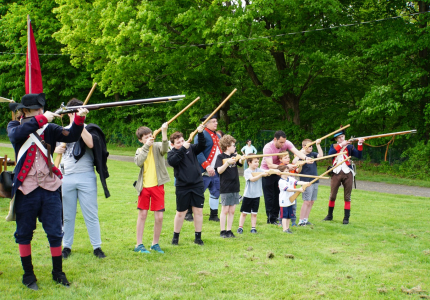 Revolutionary War reenactors target practicing with children at the Rochambeau Festival. 
