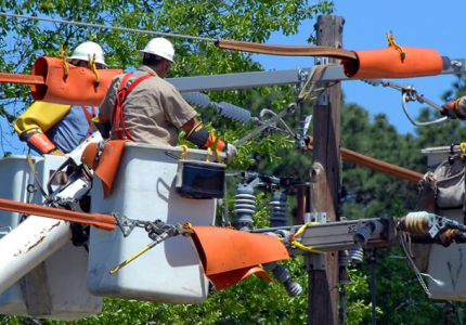 three utility workers working on pole